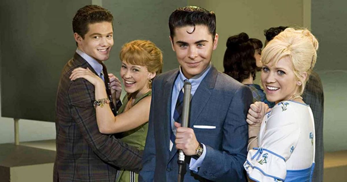 Zac Efron and a few other actors smiling for the camera